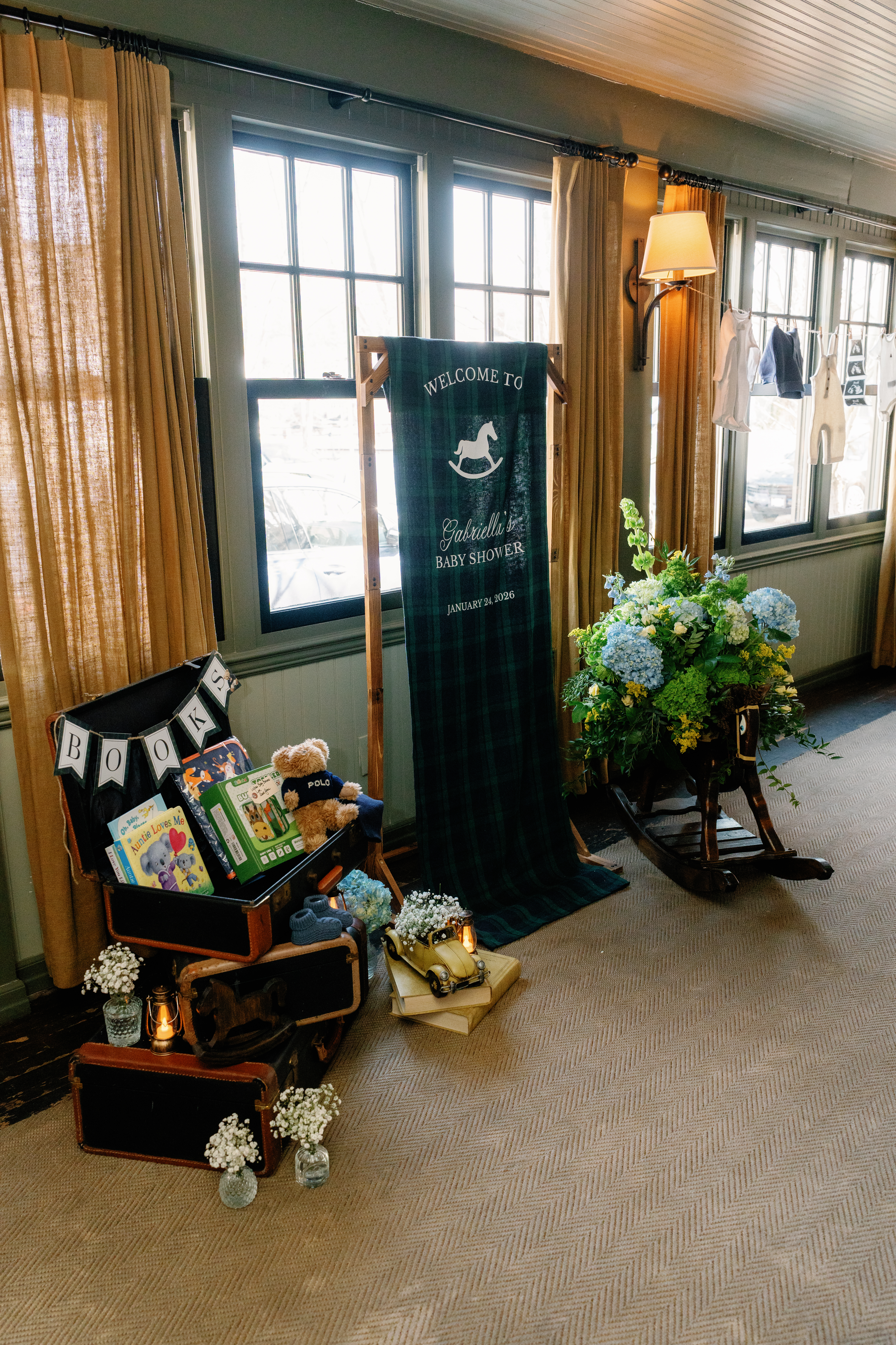 Baby shower entry display with book station, welcome banner, and clothesline