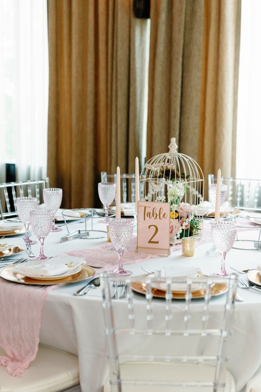 Pink and gold table setting with birdcage centerpiece and floral accents